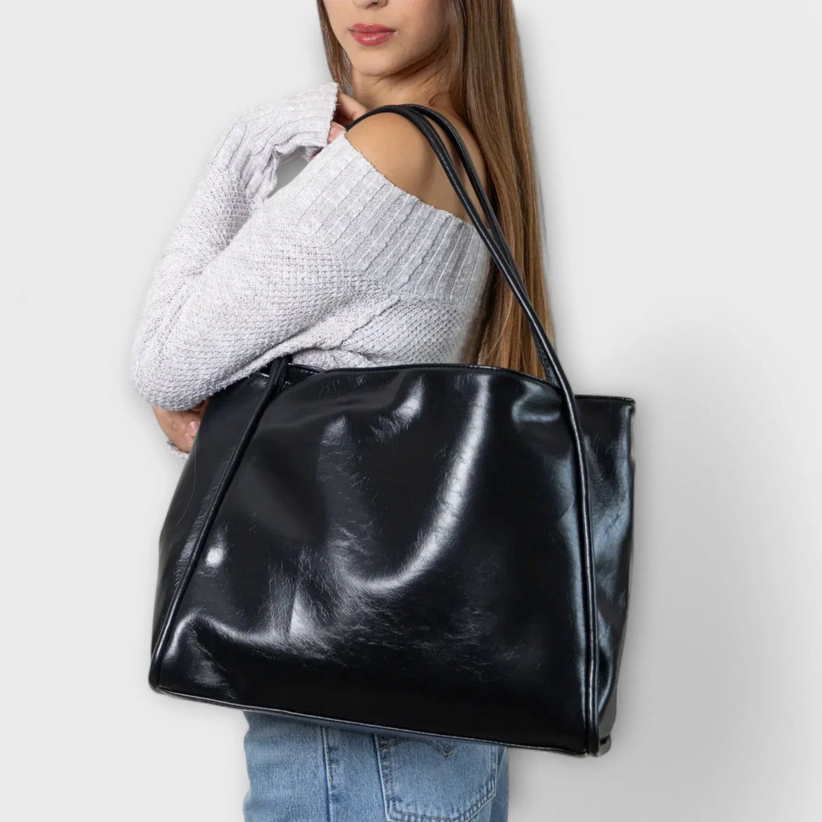 Black faux-leather tote bag, open-top, thin straps.