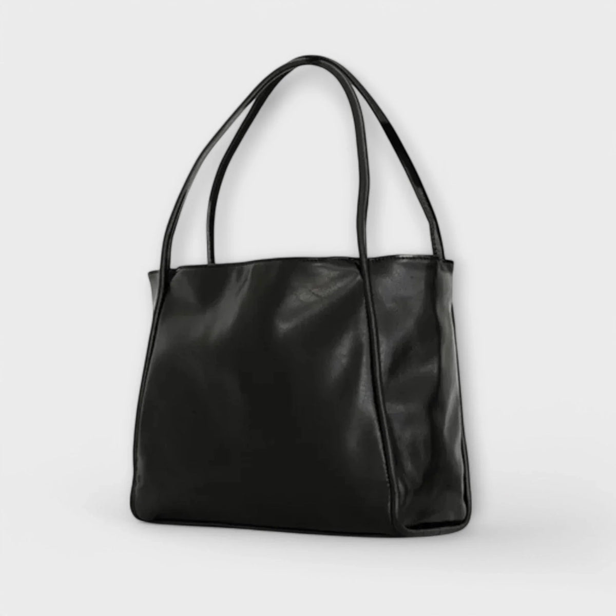 Black faux-leather tote bag, open-top, thin straps.