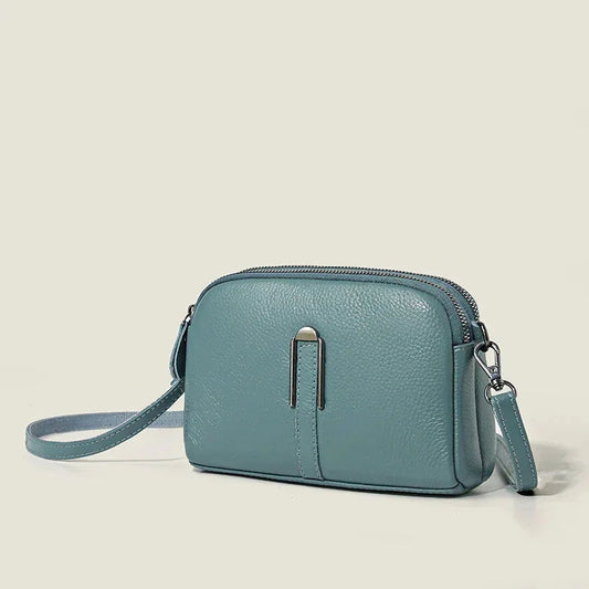 Blue leather shoulder bag with double zip closure and metal accent.