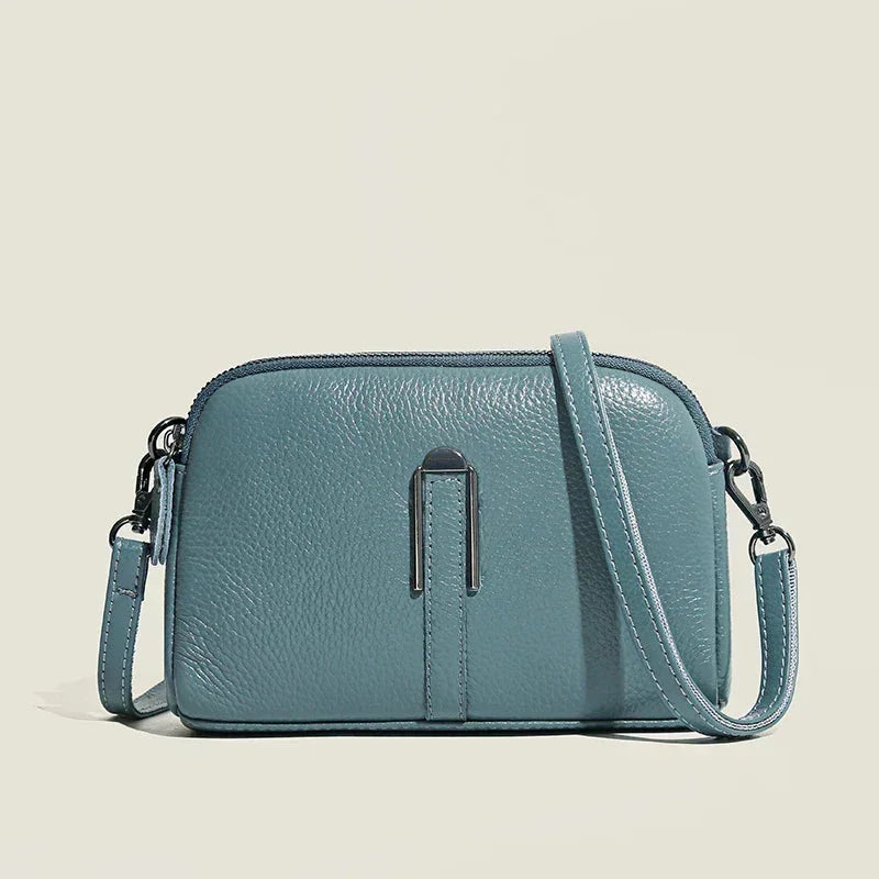 Blue leather shoulder bag with double zip closure and metal accent.