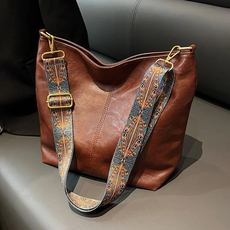 Brown faux-leather hobo bag with a wide strap featuring a bohemian pattern.