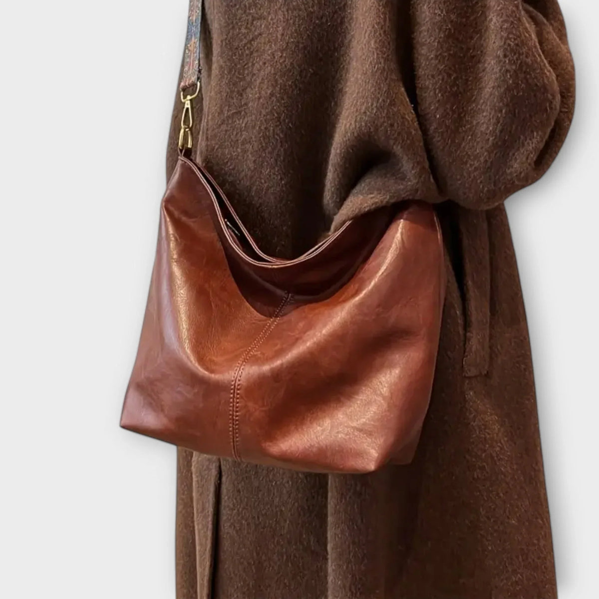 Brown faux-leather hobo shoulder bag with wide geometric patterned strap.