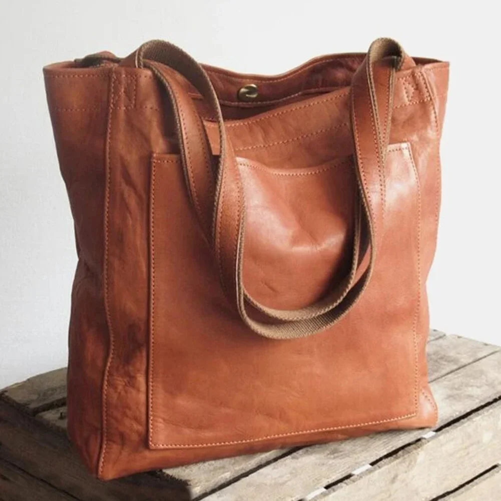 Brown leather tote bag with magnetic snap closure and front patch pocket.