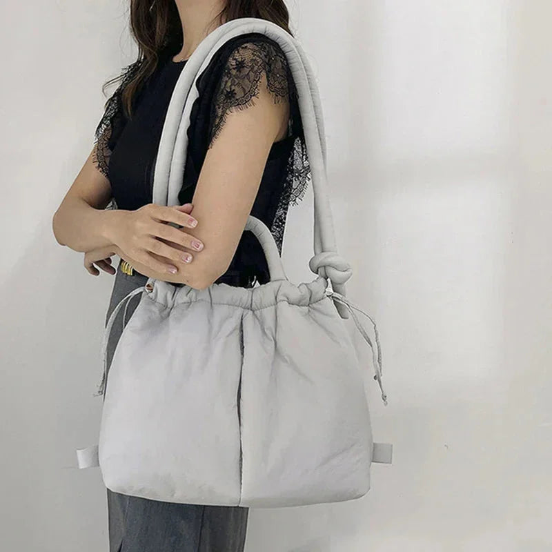 Quilted puffer tote bag with drawstring sides and knot-detail strap.