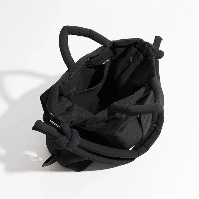Quilted puffer tote bag with drawstring sides and knot-detail strap.