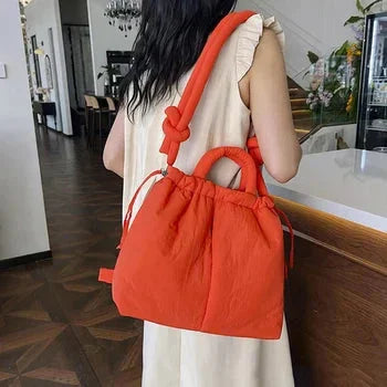 Quilted puffer tote bag with drawstring sides and knot-detail strap.