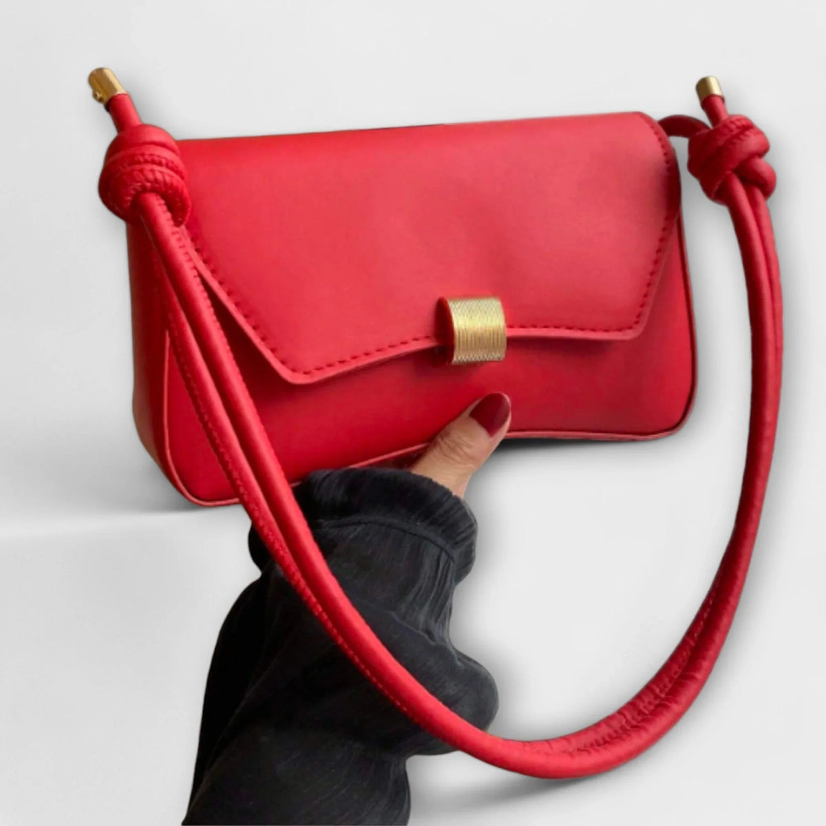 Solid colour faux leather shoulder bag with flap closure and knotted strap.