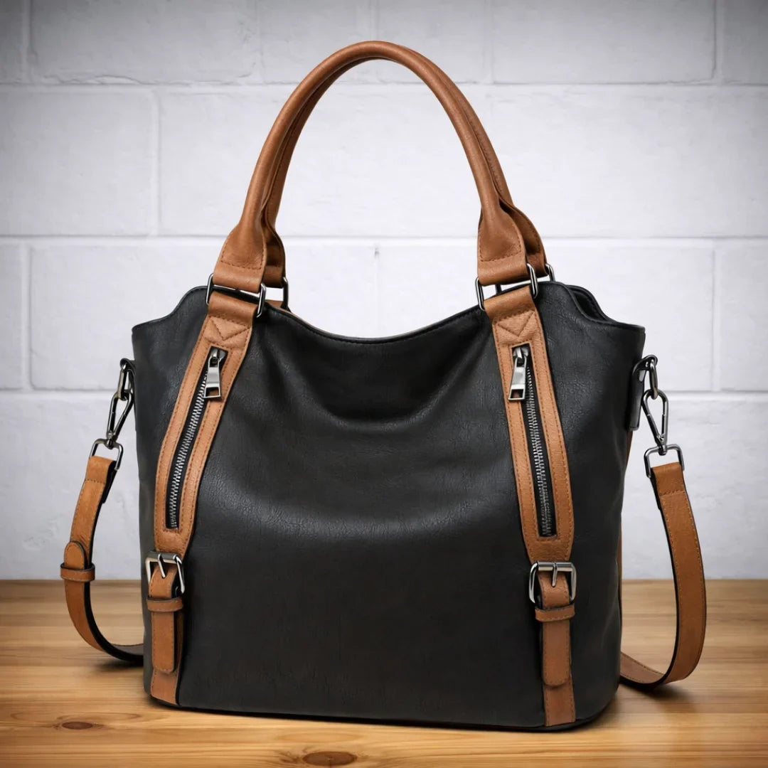 Black faux-leather slouchy crossbody bag. Brown strap, dual front zip pockets.